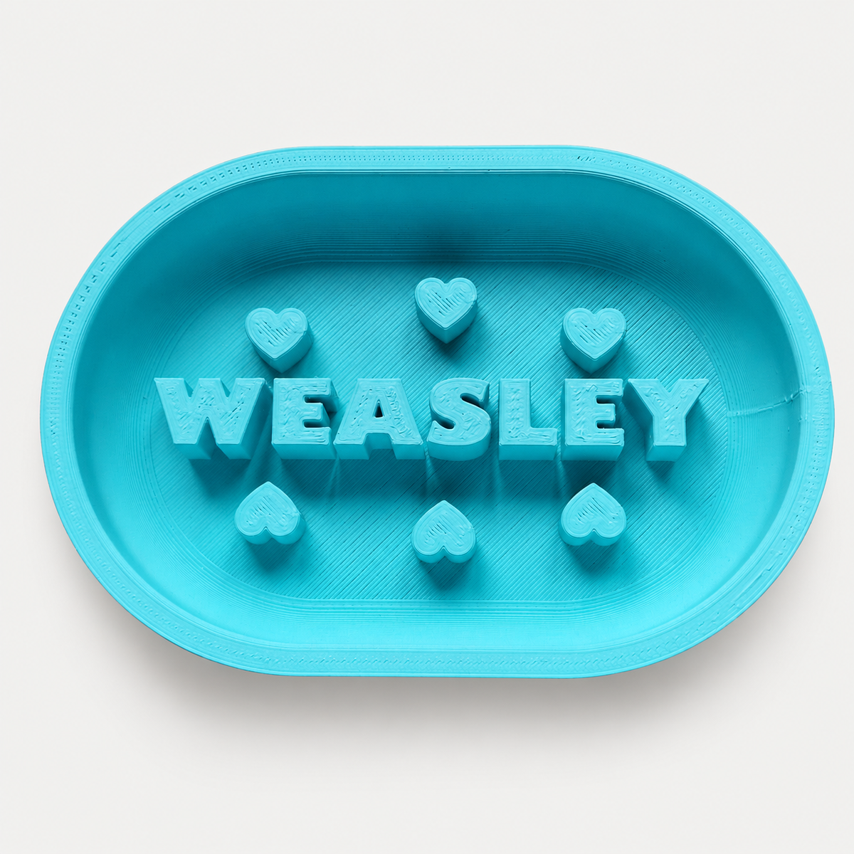 Türkiser personalisierter Slowfeeder WEASLEY mit Herzen auf neutralgrauem Hintergrund