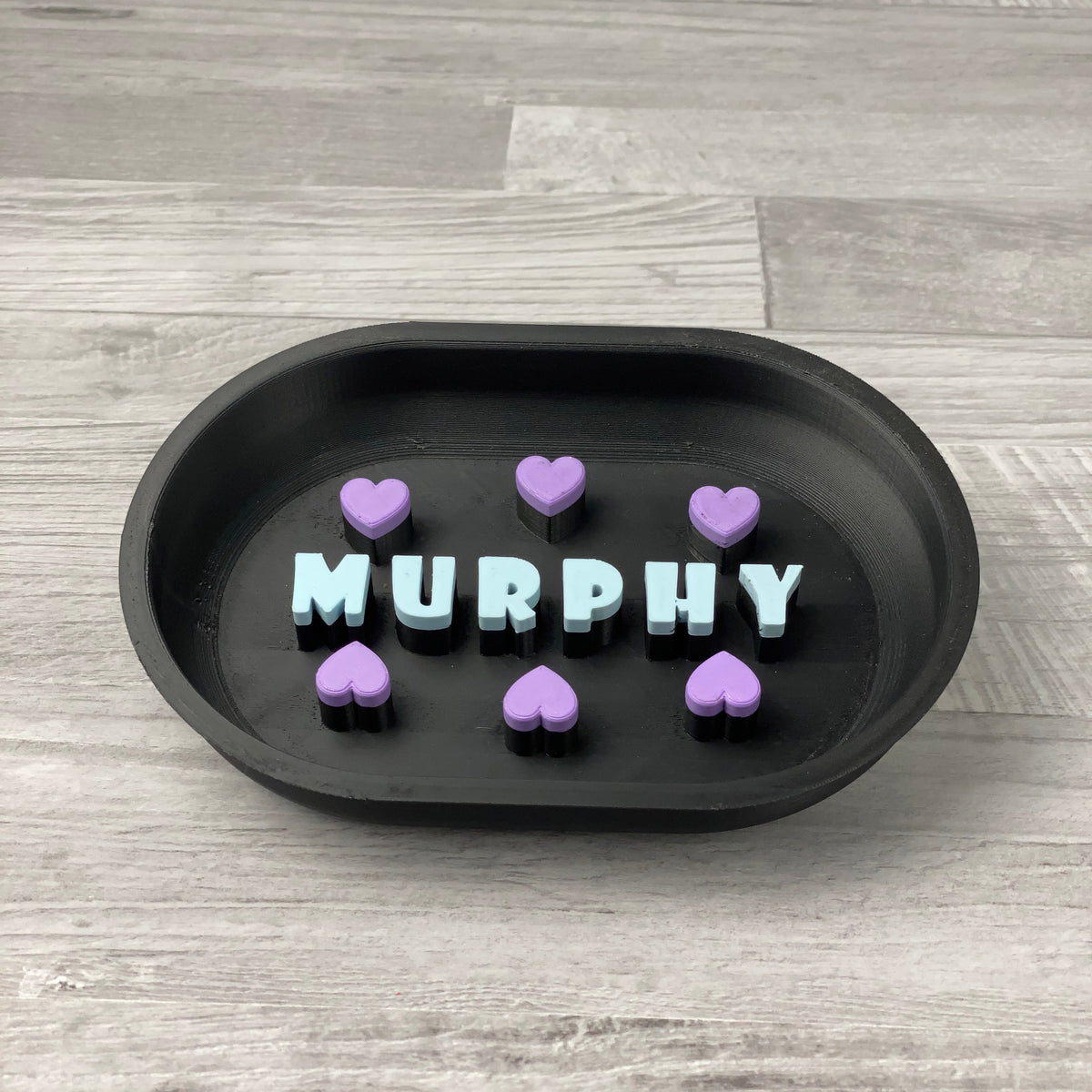 Schwarzer personalisierter Slowfeeder mit hellblauem Namen MURPHY und violetten Herzen