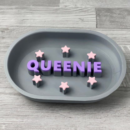 Grey personalised slow feeder with the name QUEENIE in purple and pink stars