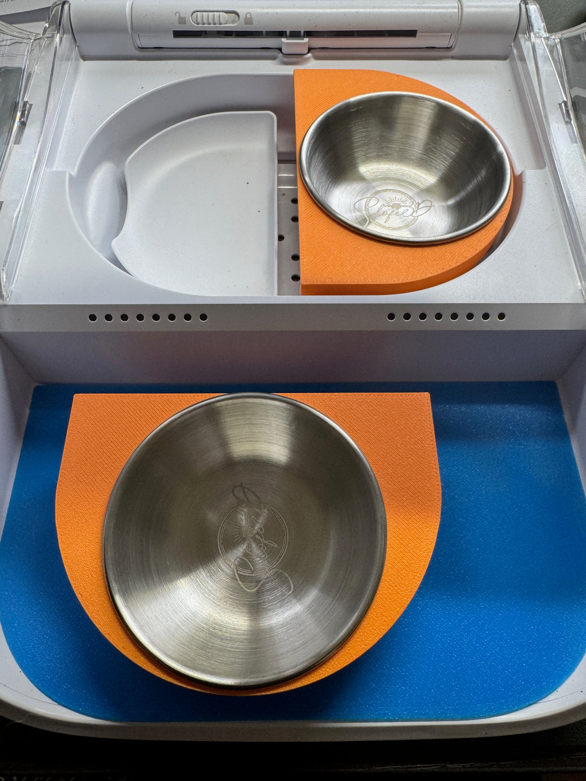 Orange split twin bowl adaptor for SureFeed Connect: two separate halves, one fitted in the feeder and one removed